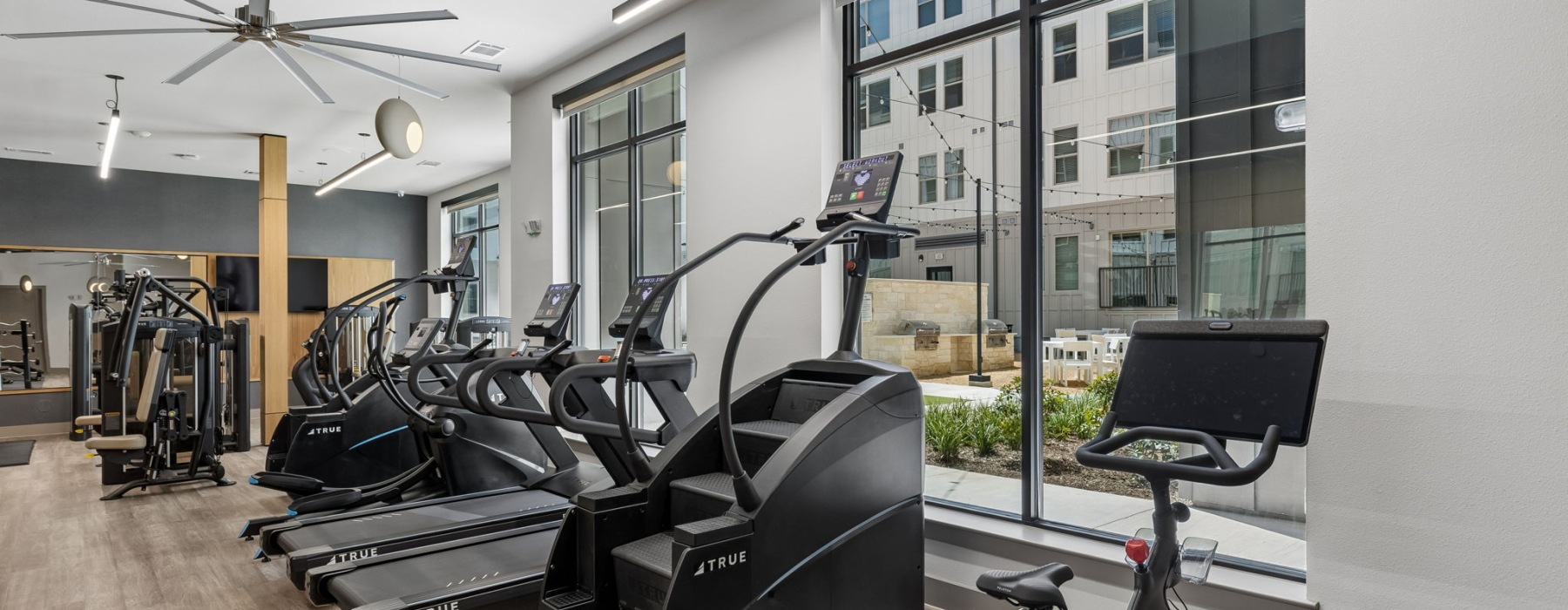 The Holland's apartment community fitness center with treadmills, stair stepper, and Peloton bike